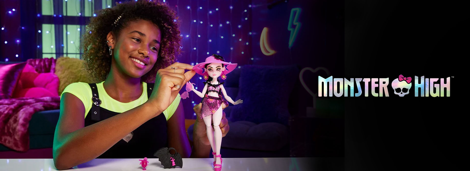 Jente leker med dukke i lysdekorert rom, Monster High-logo synlig.