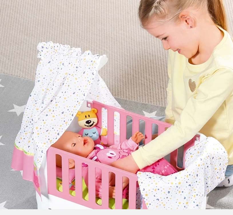 Jente leker med dukke i rosa sprinkelseng med lekegardin og bamse.