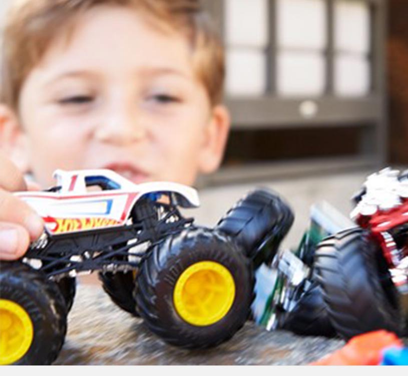 Gutt leker med lekemonstertrucker på et bord.