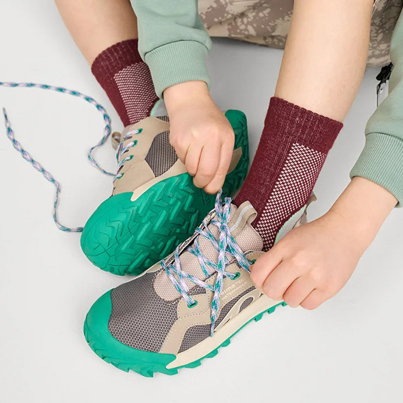 Barns brune sko med borrelås og fargerike bukser.