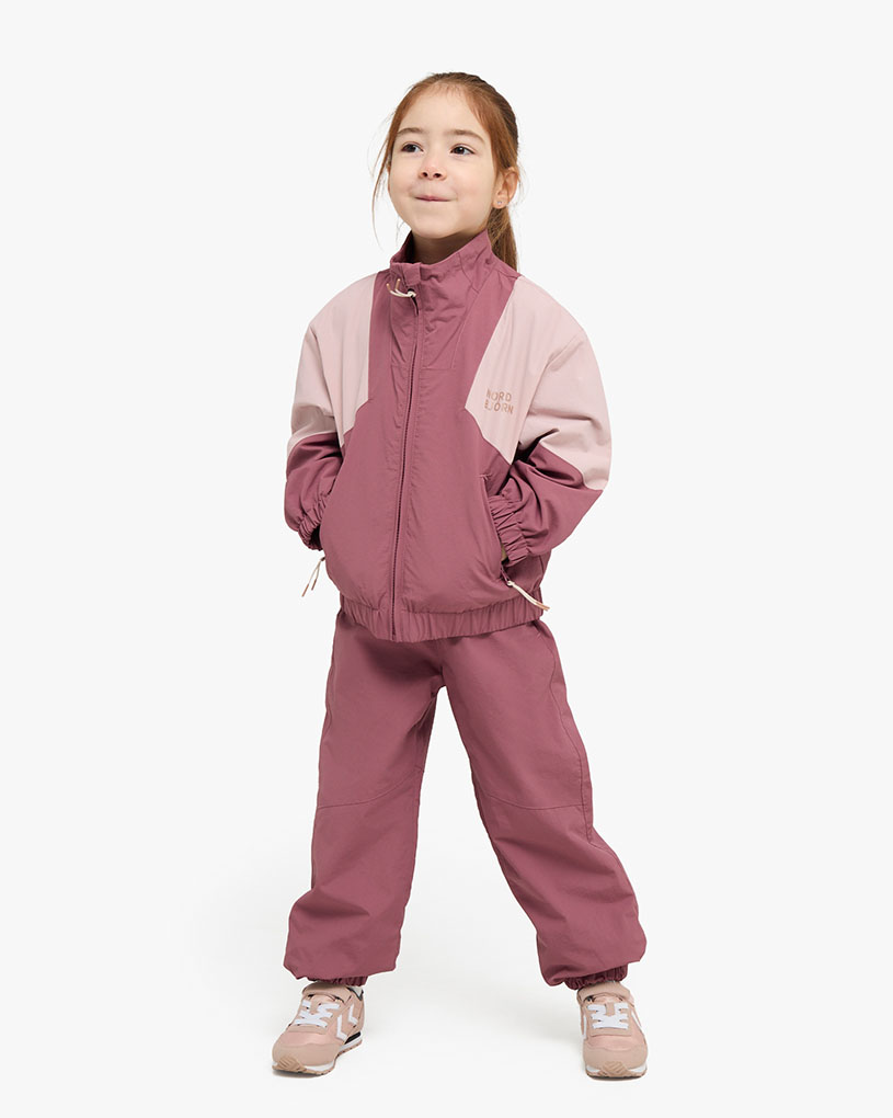 Jente i rosa stripete antrekk og caps leker ute.