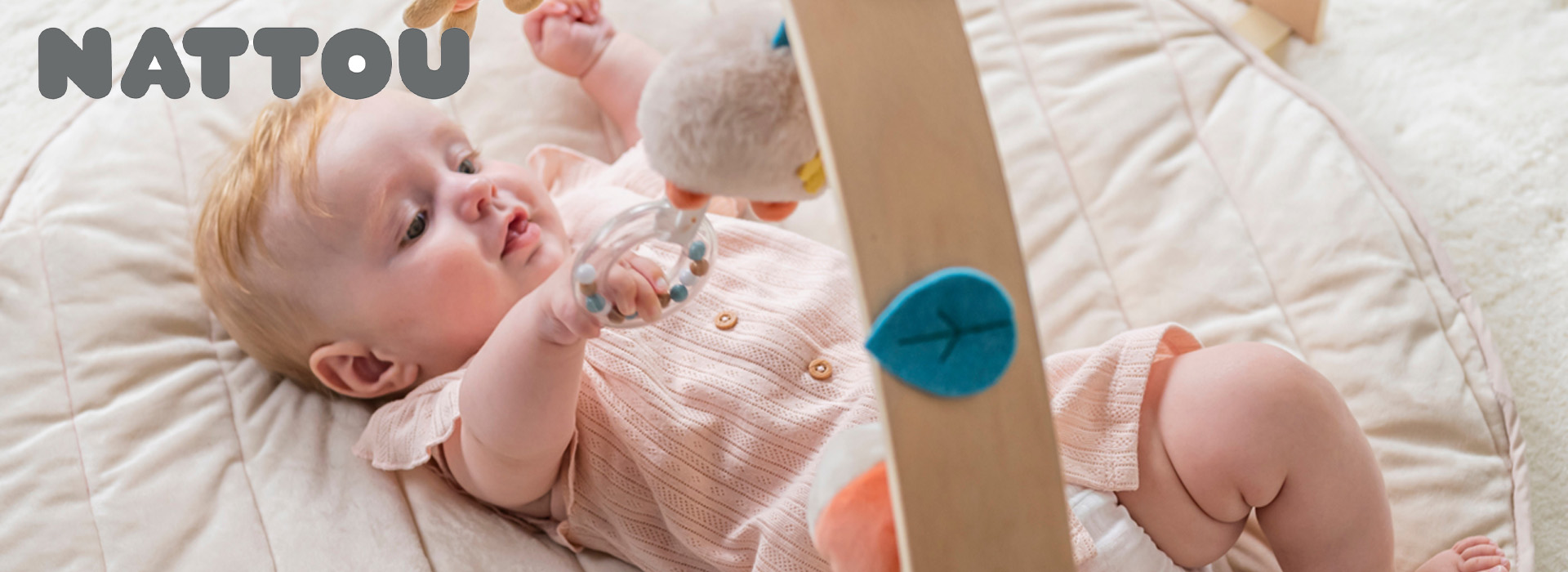 Baby leker med leketøy på mykt teppe.