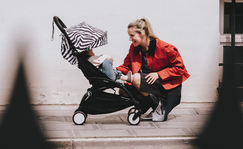 Mor ler sammen med barnet sitt i en Stokke barnevogn med sebramønstret kalesje