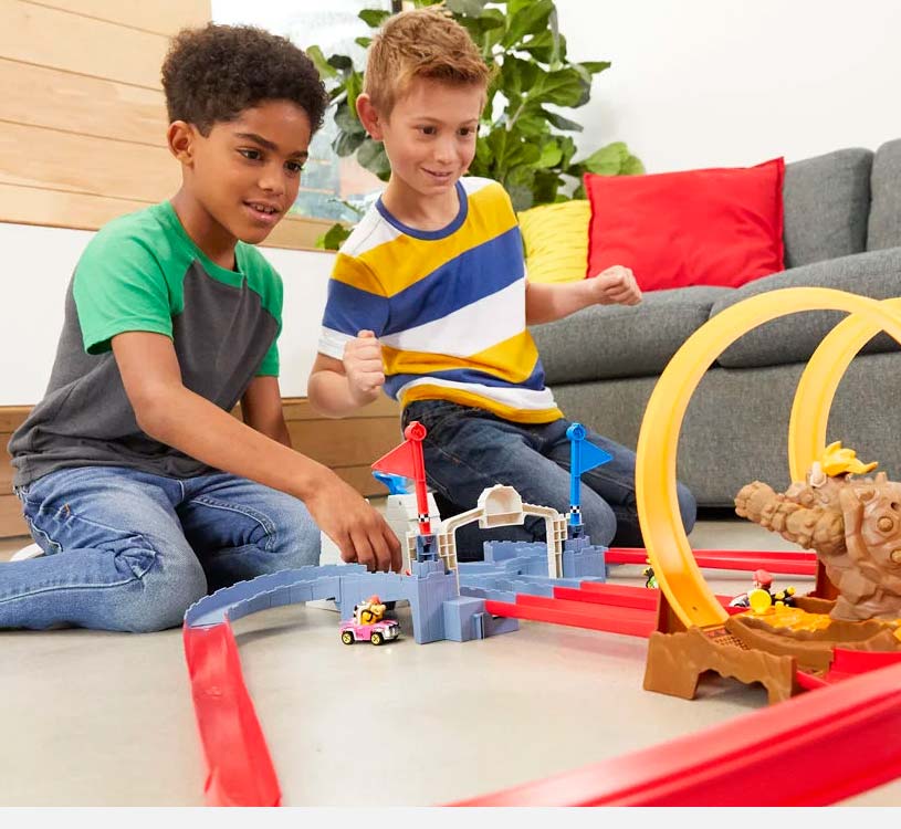 To gutter leker med en bilbane innendørs, med biler og looper.