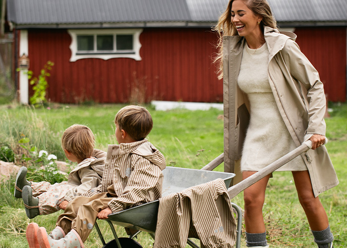 En kvinne skyver en trillebår med to barn, med teksten 'Kenza X Viking'.