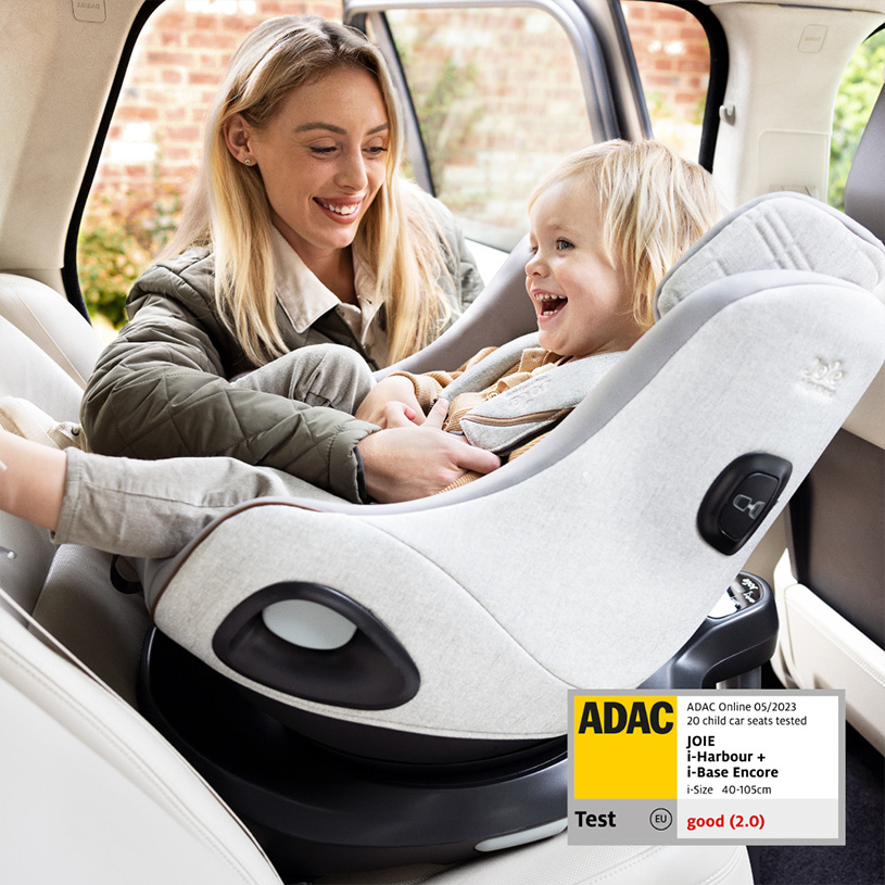 Kvinne smiler til barn i bilsete i bil.