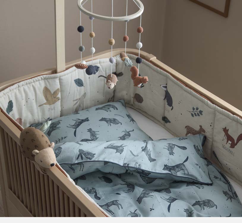 Barneseng med dyremønstrede sengetøy og hengende mobiler.