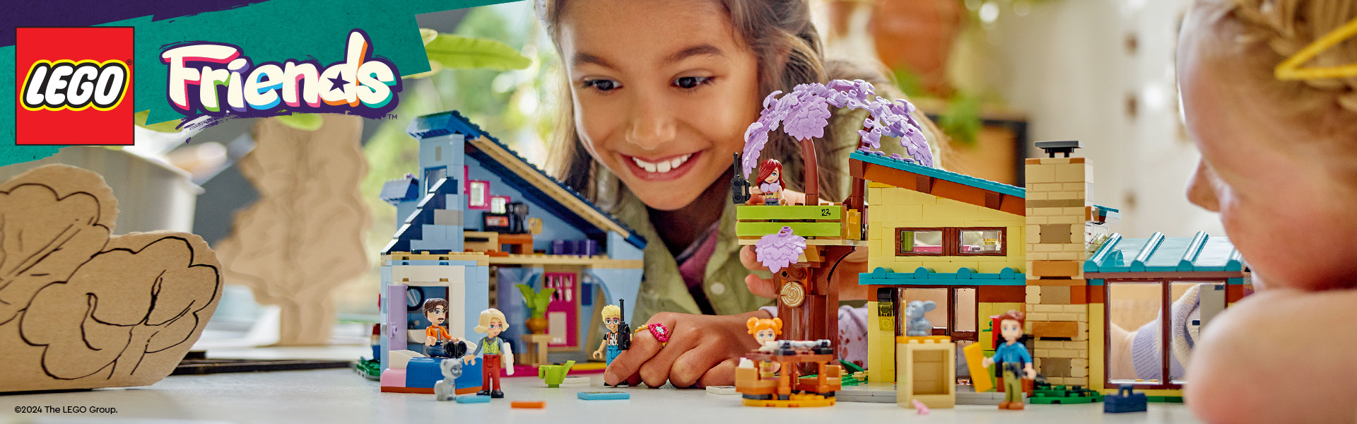 Barn leker med LEGO Friends dukkehus og figurer på et bord.