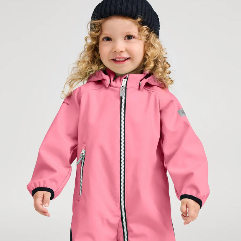 Smilende barn i oransje jakke og lilla lue.