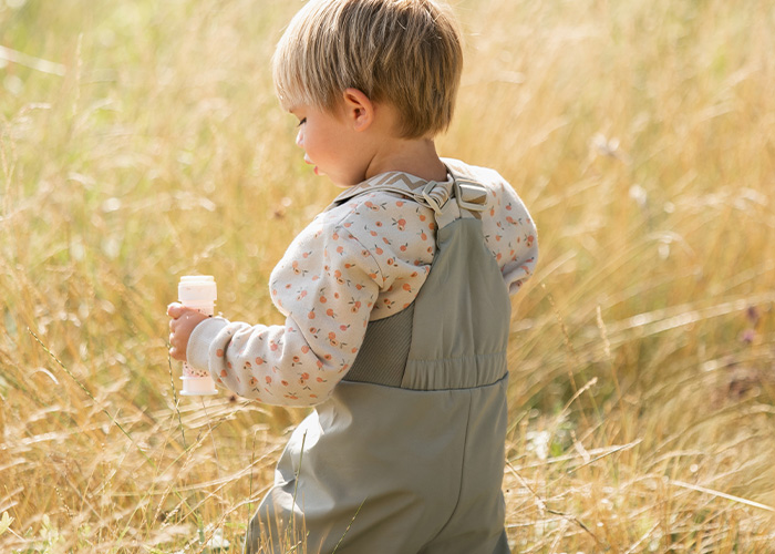 Barn i grå overaller holder en flaske, med teksten 'Kenza X Viking'.