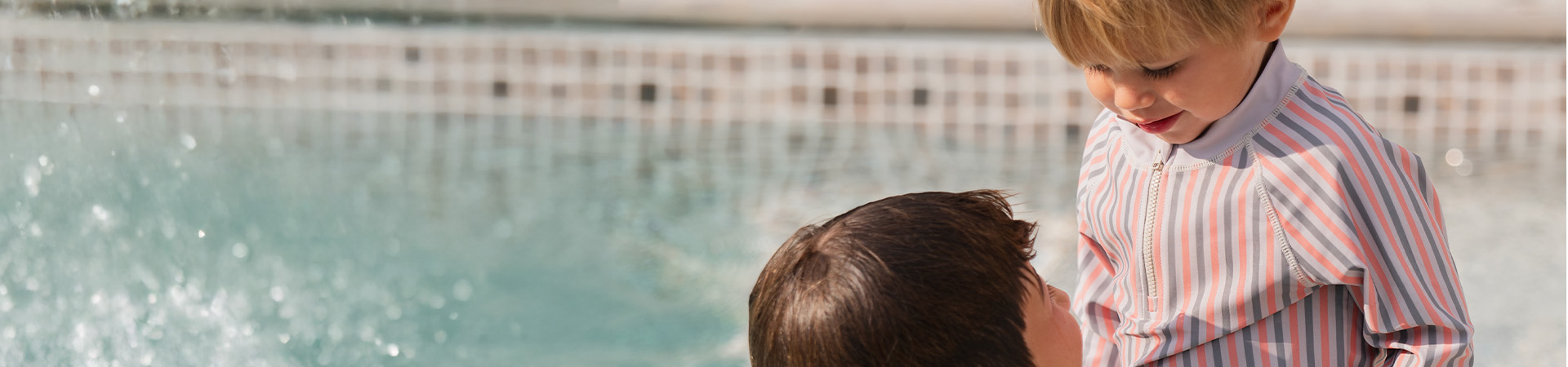 Mor smiler til barnet sitt som holder en blomst, med teksten 'Kenza X Viking'.