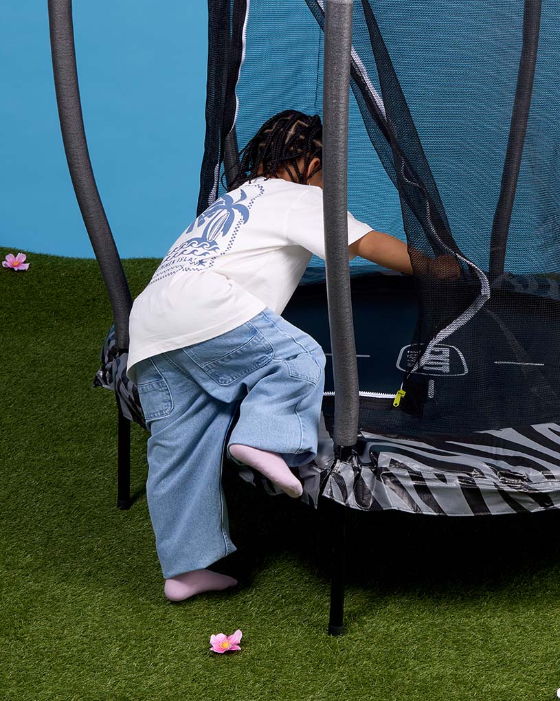 To barn sitter på et teppe med snacks i hagen.