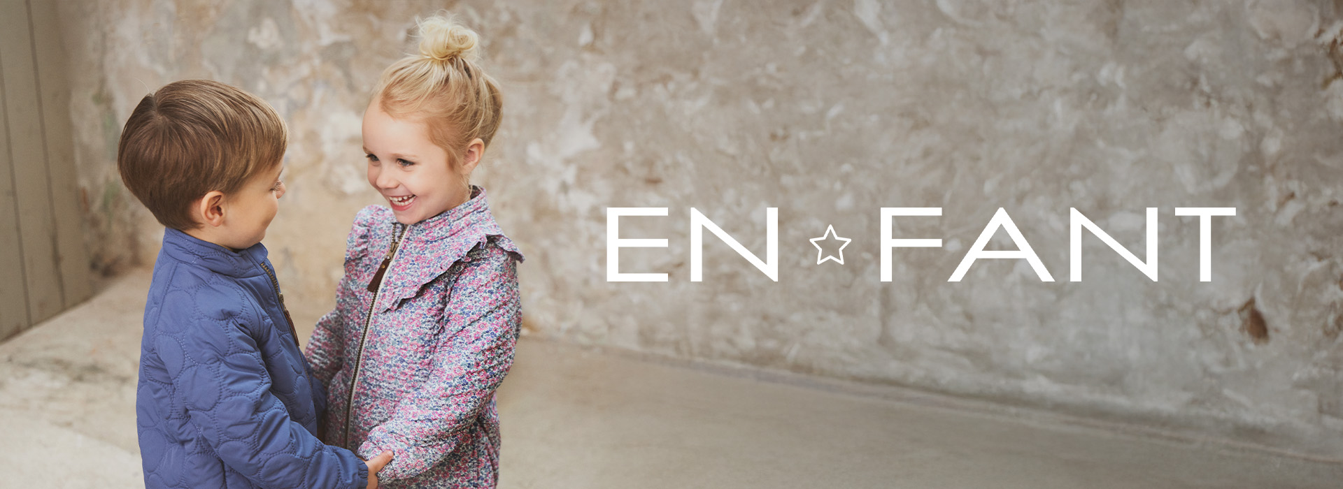 To barn smiler og holder hverandre i hendene, med teksten EN FANT ved siden av.