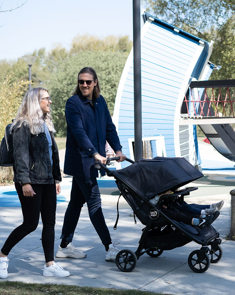 Mann og kvinne går med barnevogn ute.