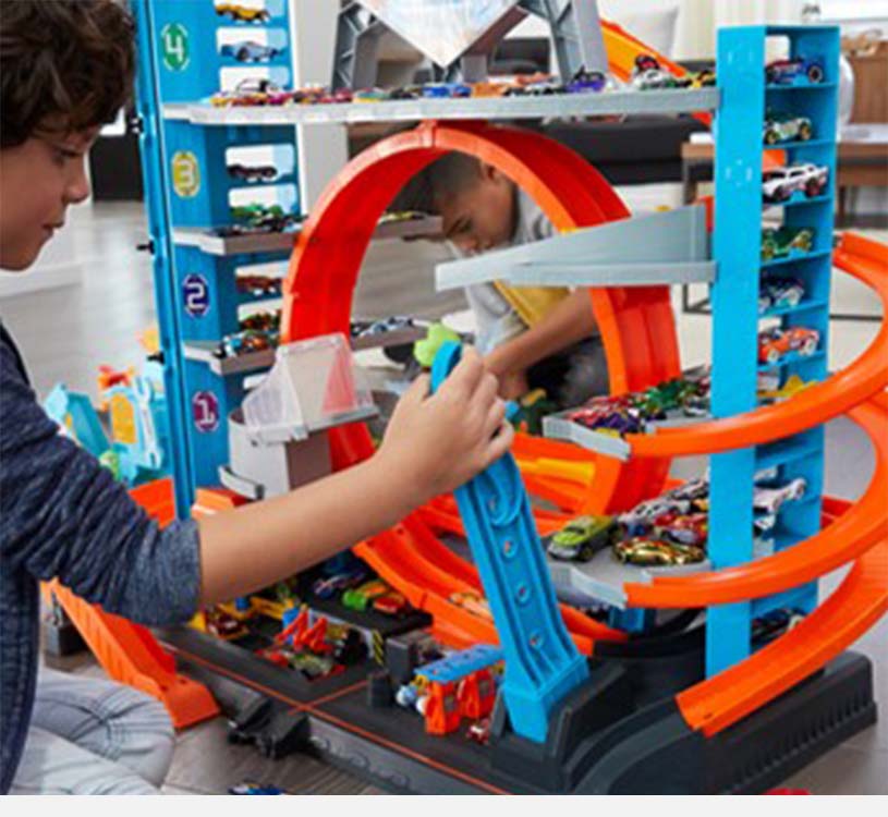 Barn leker med stor lekebilbane med oransje ramper.