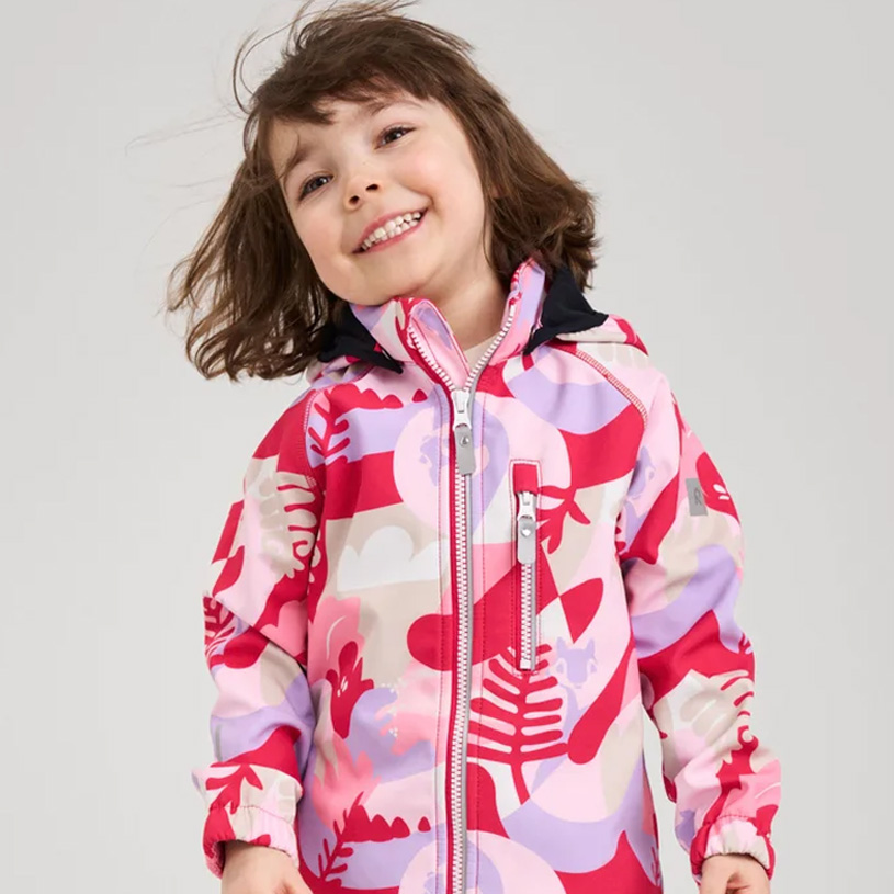 Tre barn i fargerike klær står sammen.