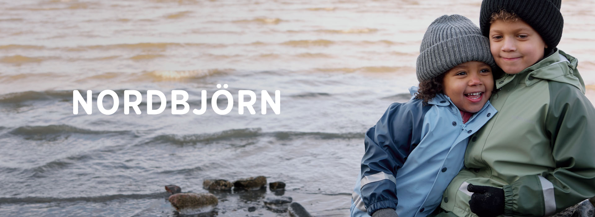 To barn i fargerike klær løper langs en tresti i et gressfelt.