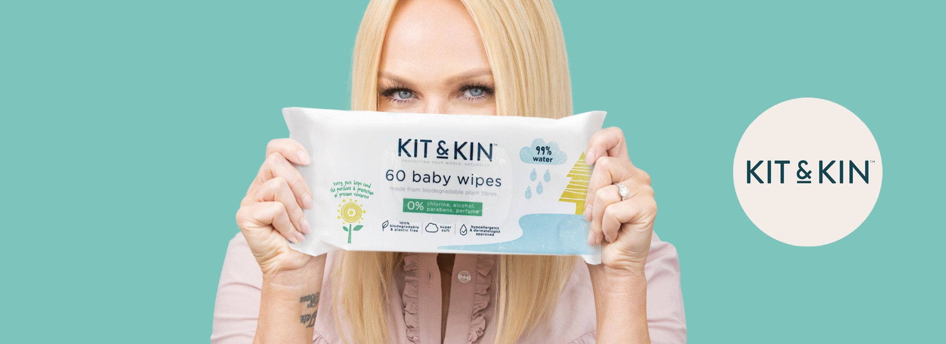 Person holder Kit & Kin babyservietter, turkis bakgrunn.