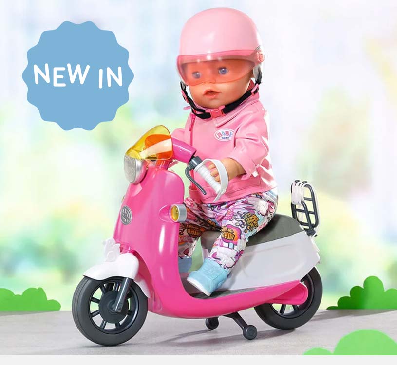 Dukke på rosa motorsykkel med hjelm, nyhetstegn i bakgrunnen.