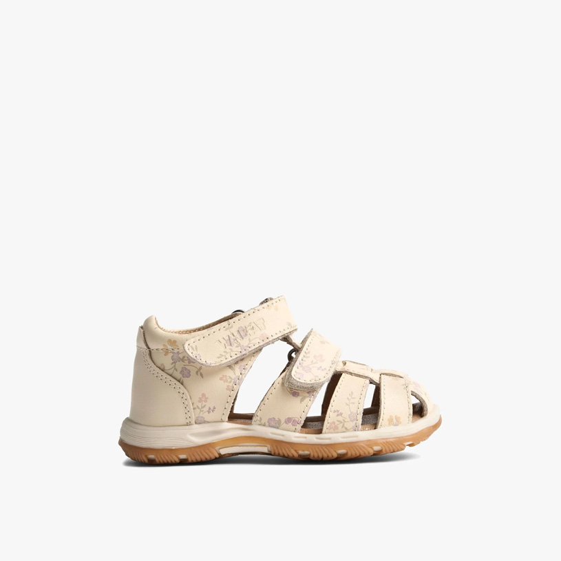 Barn i brune sandaler på trinn av rød stein.