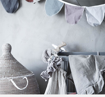 Nøytral barneromsinnredning med flettet kurv og vimpelrekke.