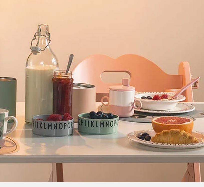 Frokostbord med juice, syltetøy og frukt i fargerike skåler.