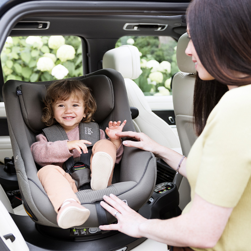 Barn i bilstol med voksen som justerer beltet.