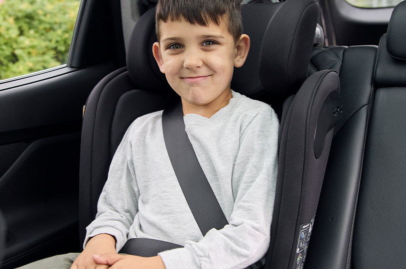 Barn i bilsete, smiler i bilen.