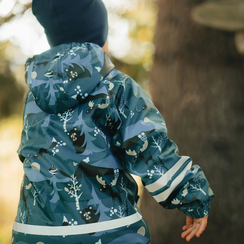 Barn i mønstret dress leker ved vannkanten.