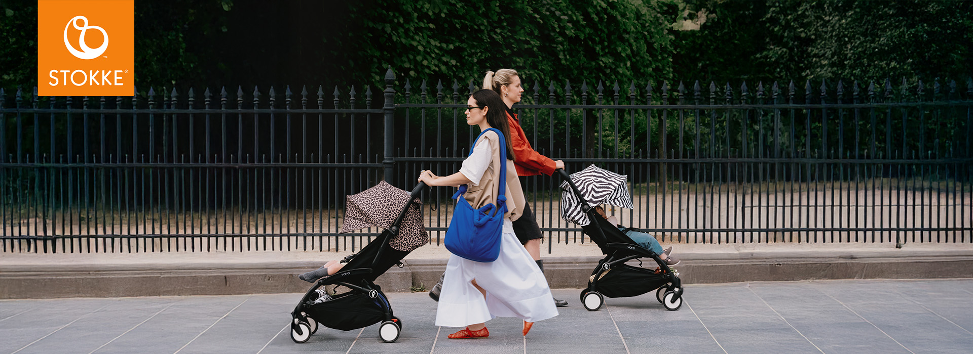 Foreldre går stilig gjennom byen med Stokke barnevogner med mønstrede kalesjer