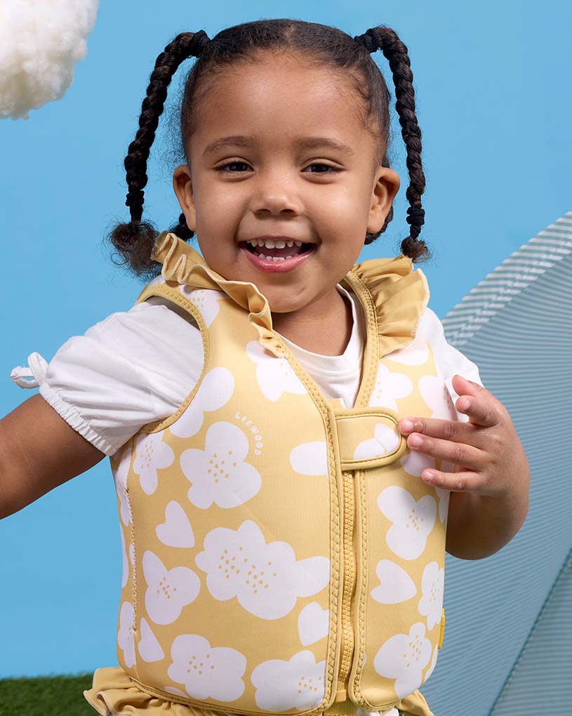 Blondt barn med armkrok med måkemotiv sitter ved bassenget.