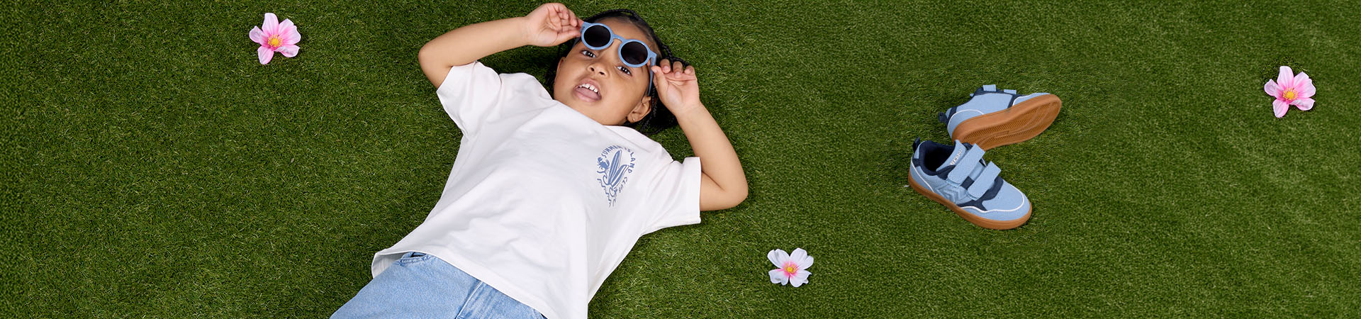 Kvinne med to små barn utendørs nær sykkelvogn og bygninger i bakgrunnen.