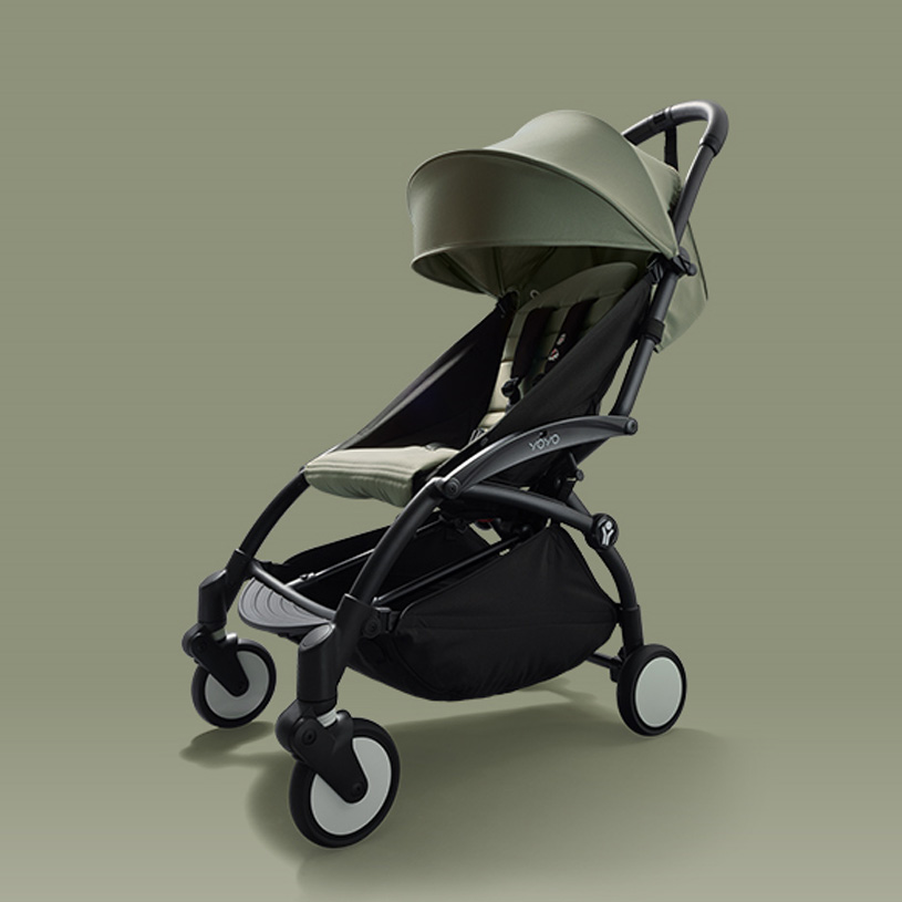 Grønn barnevogn med sort ramme på grønn bakgrunn.