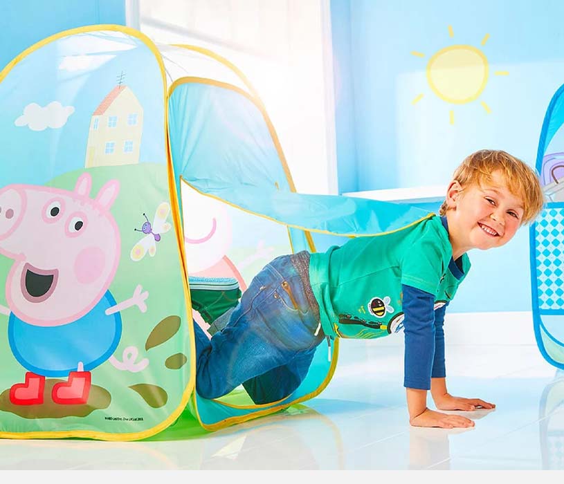 Barn kryper gjennom leketelt med Peppa Gris-motiv i solfylt rom.