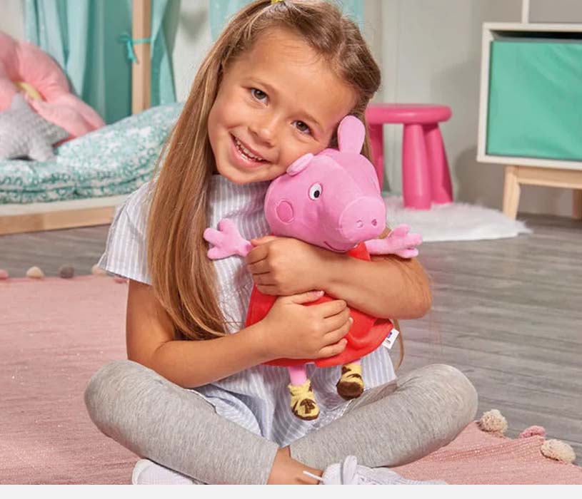 Jente med langt hår klemmer et rosa leketøy på et barnerom.