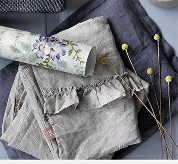 Grå linstoffer og blomsterpapir ved tørkede gule blomster på et bord.