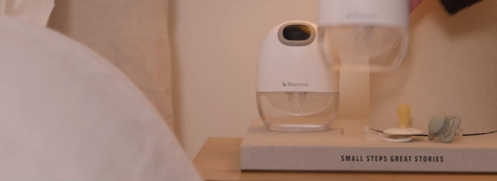 Kvinne smiler til barn i barnevogn innendørs.