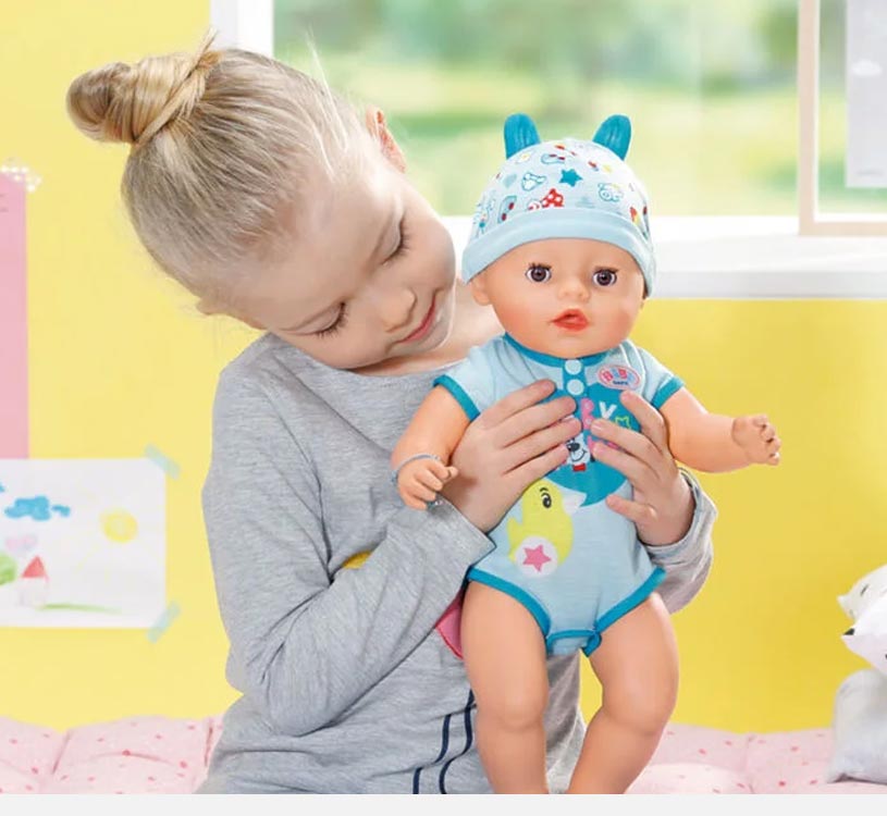 Jente holder en dukke i blå klær med lue med ører.