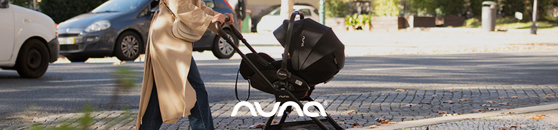 Kvinne med Nuna-bilsete og baby, vist på tur utendørs.