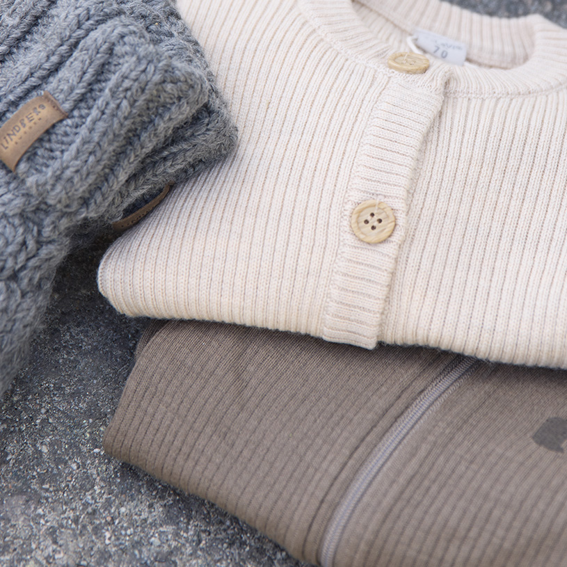 To barn i dresser, ett smiler og det andre holder et blad.