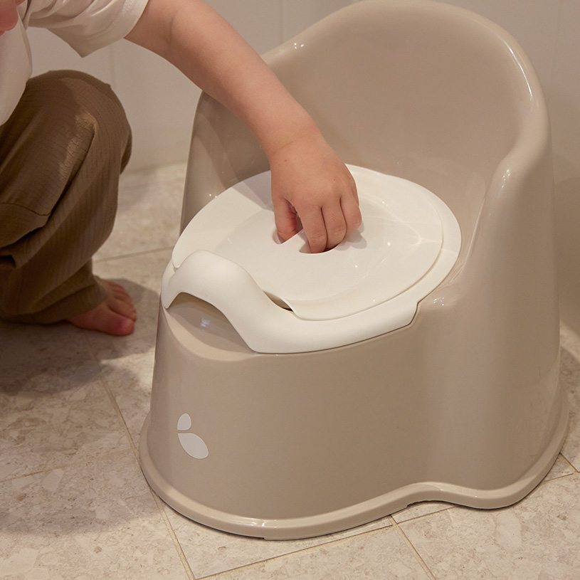Barn på potte som holder mamma i hånden. 