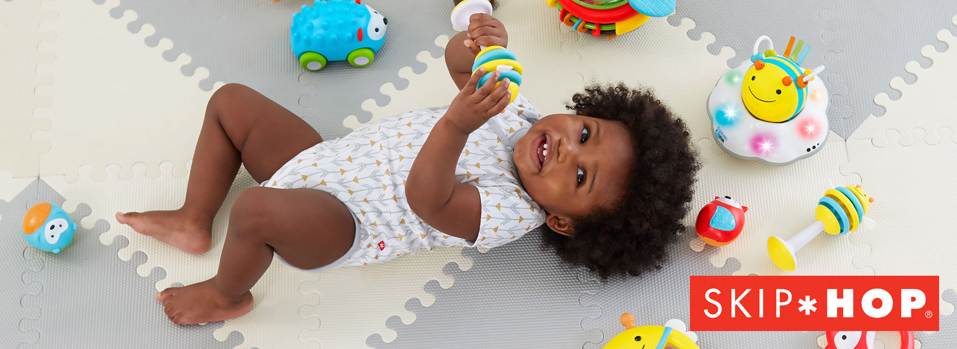 Baby leker med fargerikt leker på lekematte.