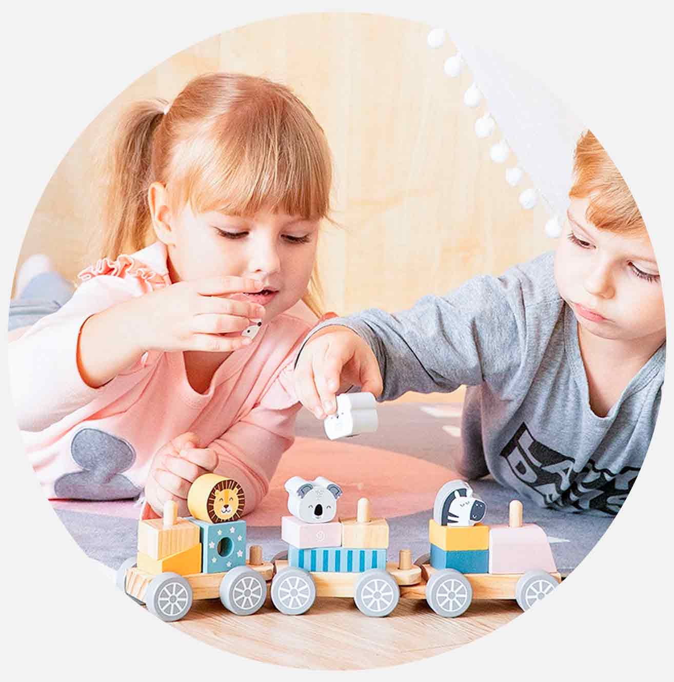 To barn leker med et treleketøy tog på gulvet.